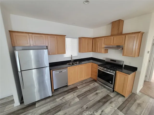 a kitchen with granite countertop a refrigerator stove top oven and sink