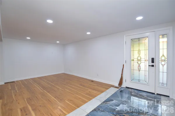 a view of an empty room with wooden floor and windows