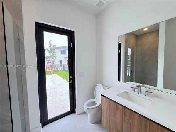 a bathroom with a granite countertop sink toilet and mirror