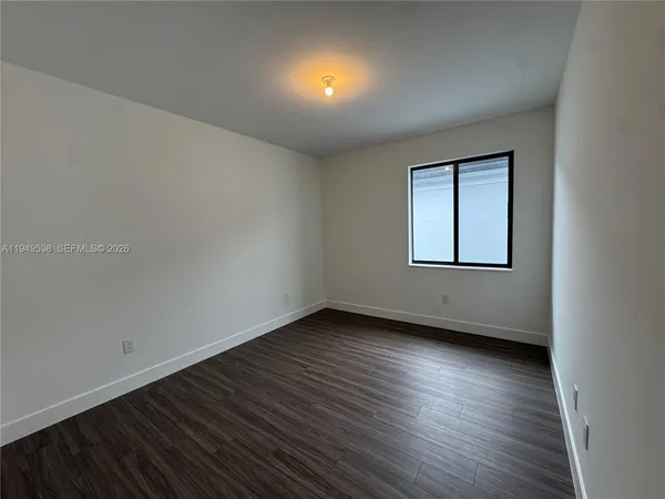 a view of an empty room with wooden floor and closet