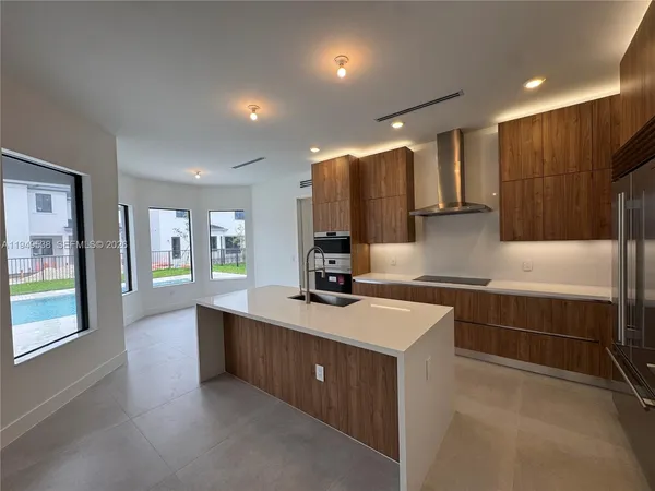 a kitchen with kitchen island granite countertop a sink and a stove top oven with wooden floor