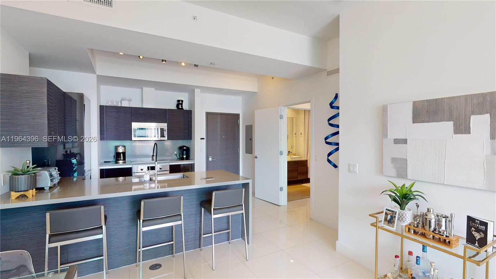 1080 Brickell Avenue, Unit 2804 Miami, FL 33131 - Photo 20 of 35 a kitchen with stainless steel appliances a sink a table and chairs in it