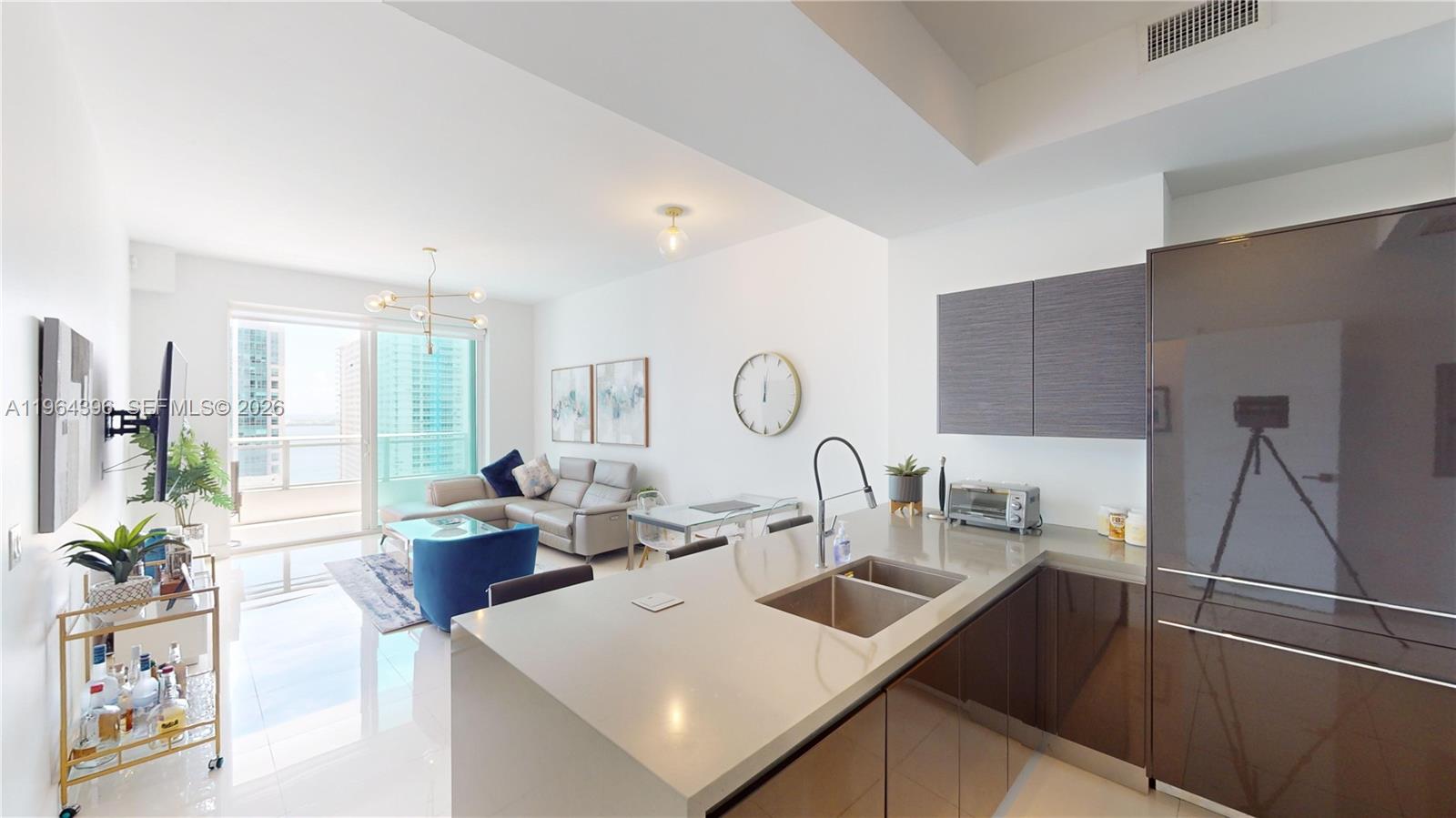 1080 Brickell Avenue, Unit 2804 Miami, FL 33131 - Photo 6 of 35 a kitchen with a sink a counter top space and living room filled with furniture