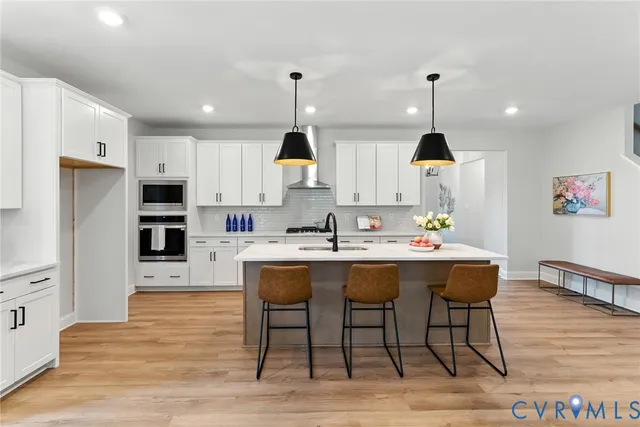 a kitchen with stainless steel appliances a dining table chairs sink and cabinets