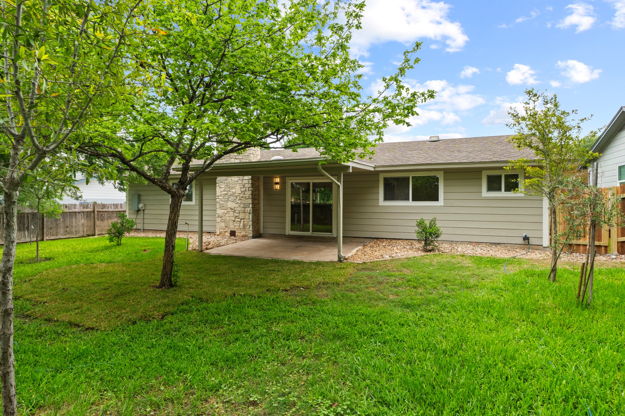 1608 Springer Lane Austin, TX 78758 - Photo 33 of 35 Expansive green lawn with mature trees and a paved patio area