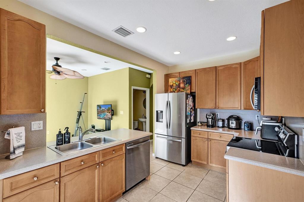 3303 Merrick Lane, Unit 1002 Margate, FL 33063 - Photo 10 of 33 a kitchen with sink a refrigerator and cabinets