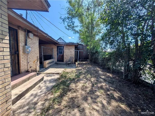 a view of yellow house with a yard and large tree