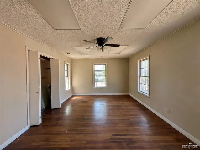 a view of empty room with wooden floor and fan