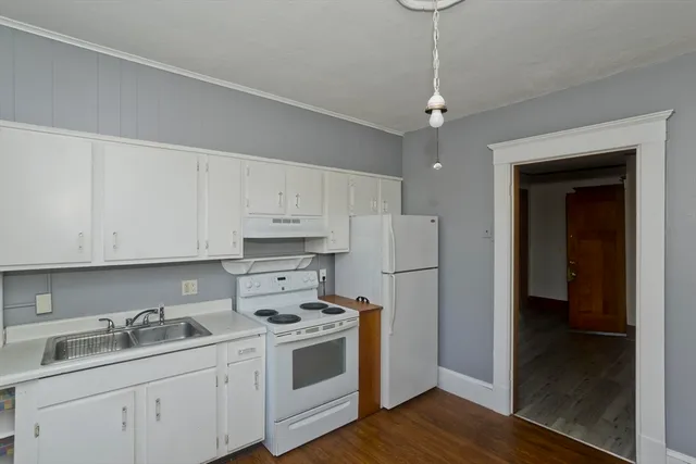 a kitchen with stainless steel appliances granite countertop a refrigerator a sink dishwasher and white cabinets with wooden floor