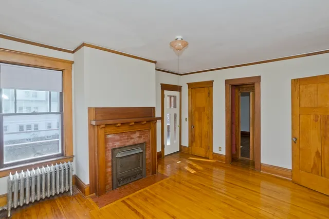 a view of a livingroom with wooden floor and a fireplace