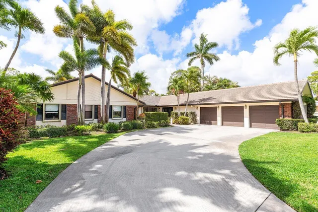 a front view of a house with a garden and trees