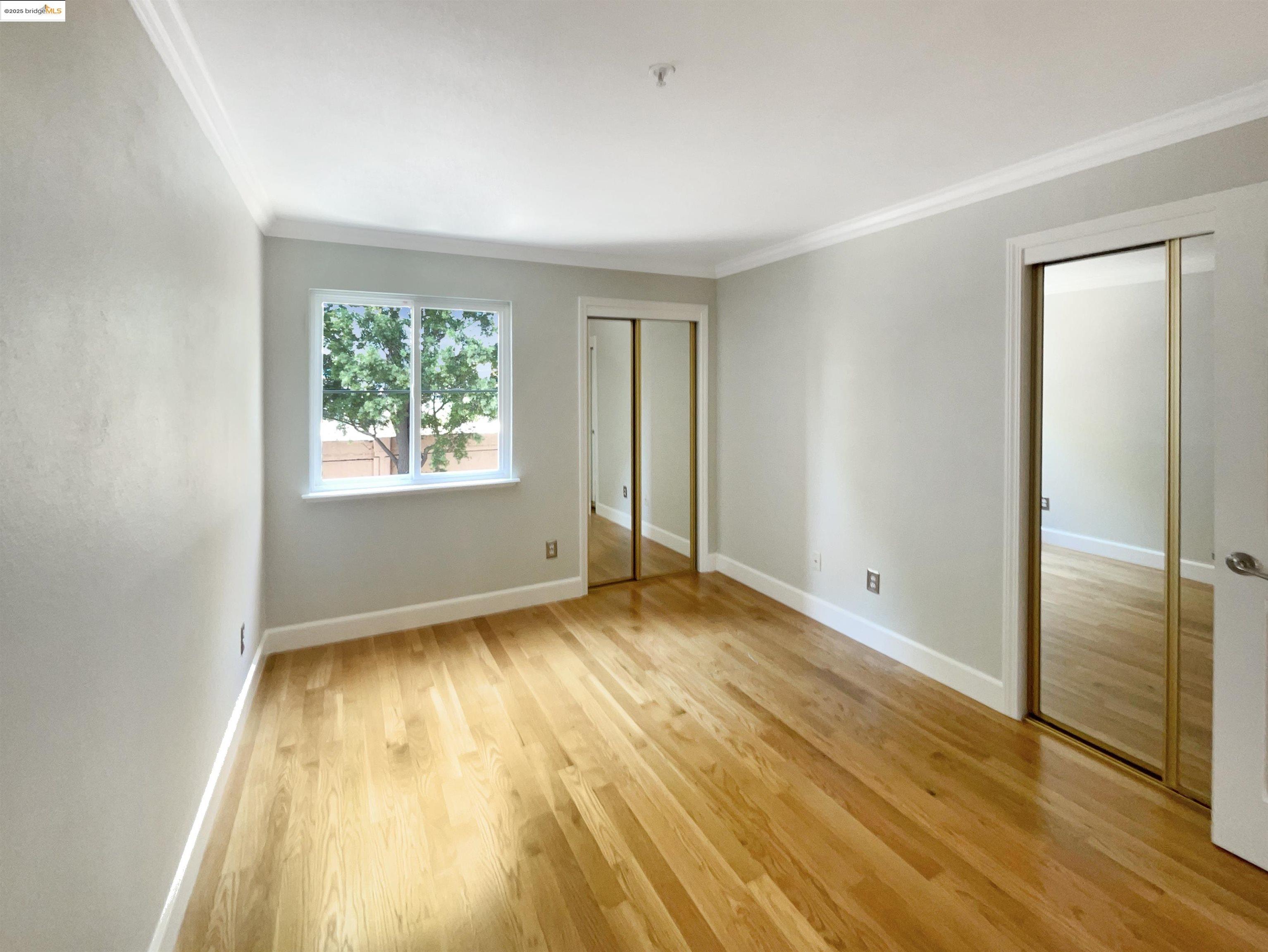 991 Asilomar Terrace, Unit 1 Sunnyvale, CA 94086 - Photo 12 of 20 Unfurnished bedroom featuring two closets, light wood-style floors, and ornamental molding