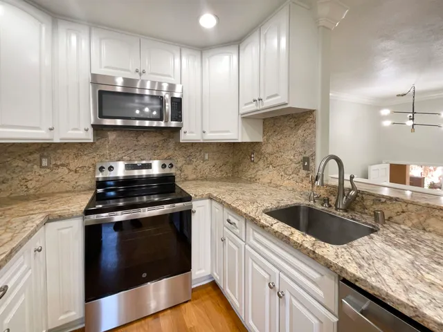 a kitchen with granite countertop white cabinets and stainless steel appliances
