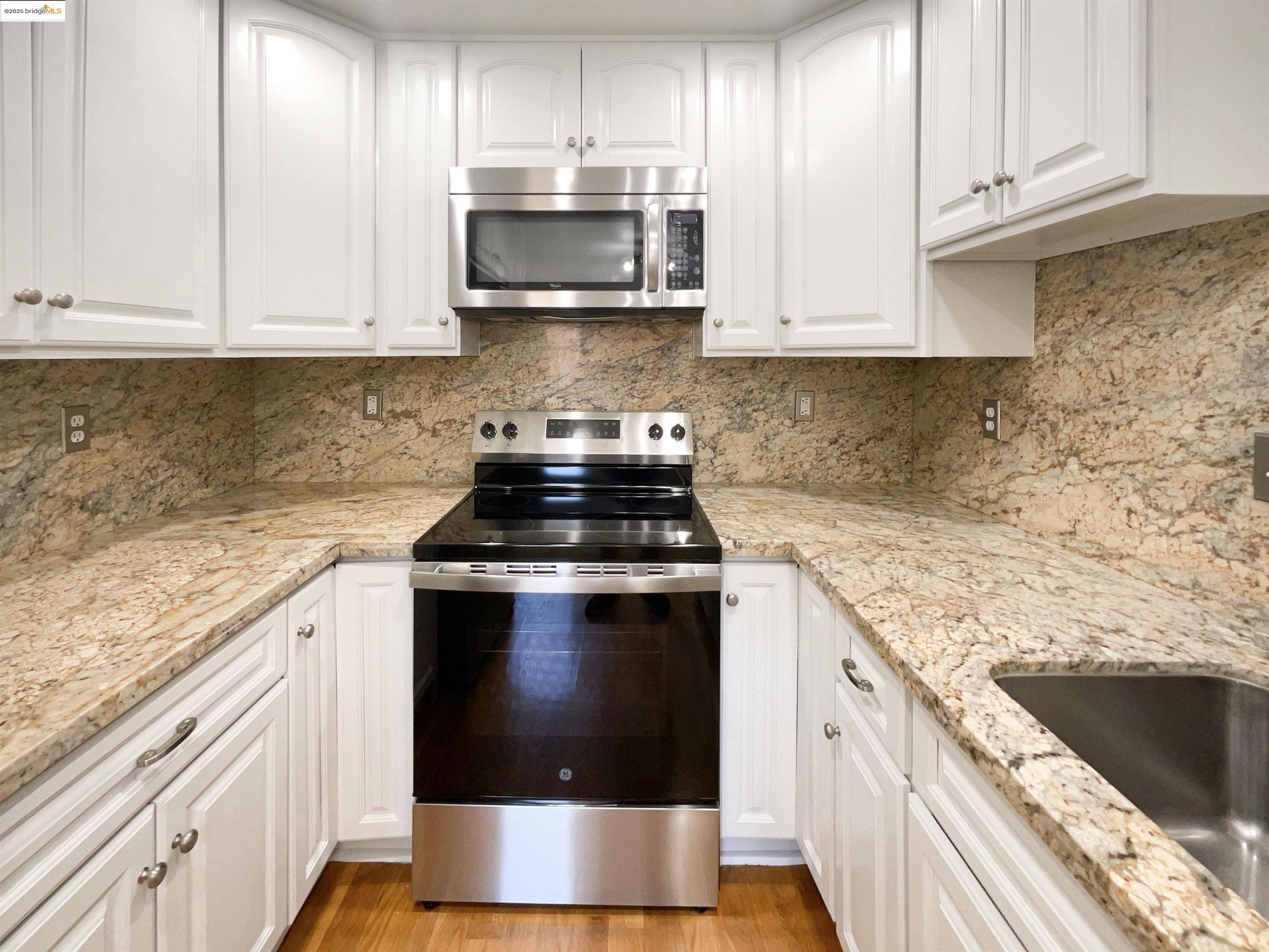 991 Asilomar Terrace, Unit 1 Sunnyvale, CA 94086 - Photo 7 of 20 Kitchen with appliances with stainless steel finishes, white cabinets, light wood finished floors, and light stone countertops