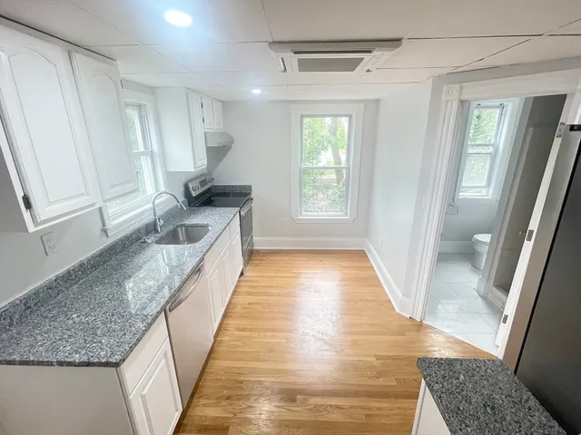 a kitchen with granite countertop a sink stove and cabinets