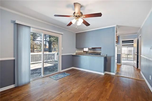 a view of a kitchen with wooden floor a ceiling fan and windows