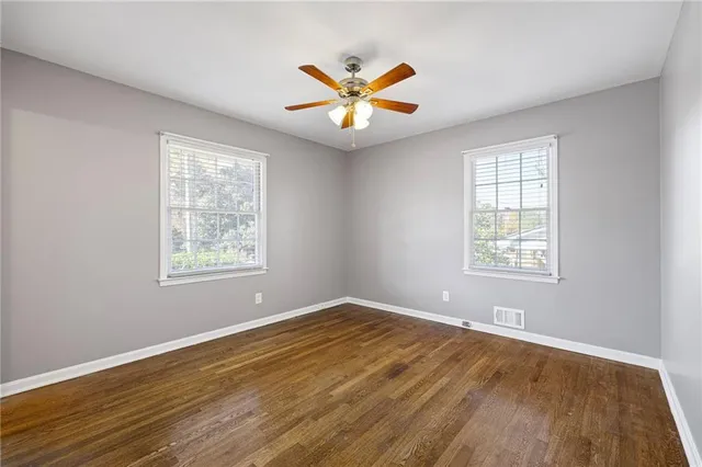 a view of an empty room with window and wooden floor