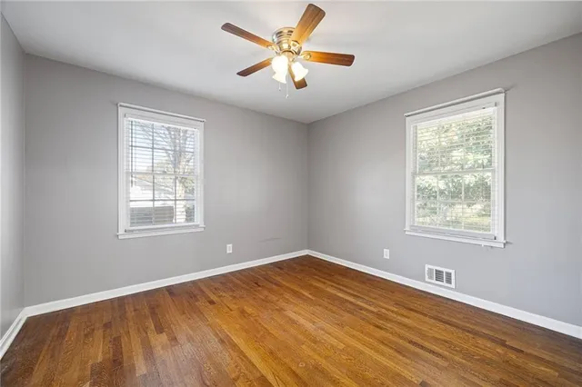 a view of empty room with wooden floor and fan