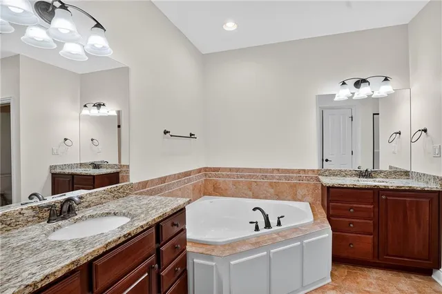 a bathroom with a granite countertop bathtub sink and mirror