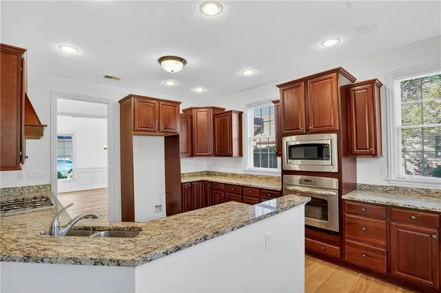 a kitchen with kitchen island granite countertop wooden cabinets a refrigerator and a sink