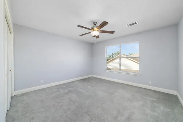 an empty room with windows and chandelier fan