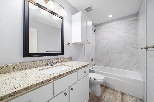 a bathroom with a granite countertop sink a toilet and a large mirror