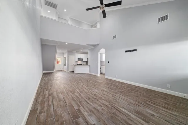 an empty room with wooden floor a ceiling fan and windows
