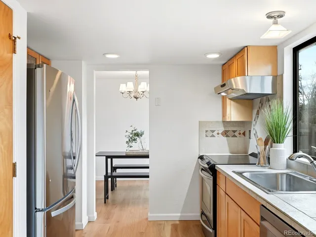 a kitchen with stainless steel appliances granite countertop a refrigerator a sink a stove and a refrigerator
