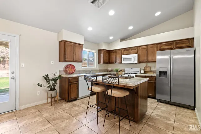 a kitchen with granite countertop a refrigerator and a stove top oven