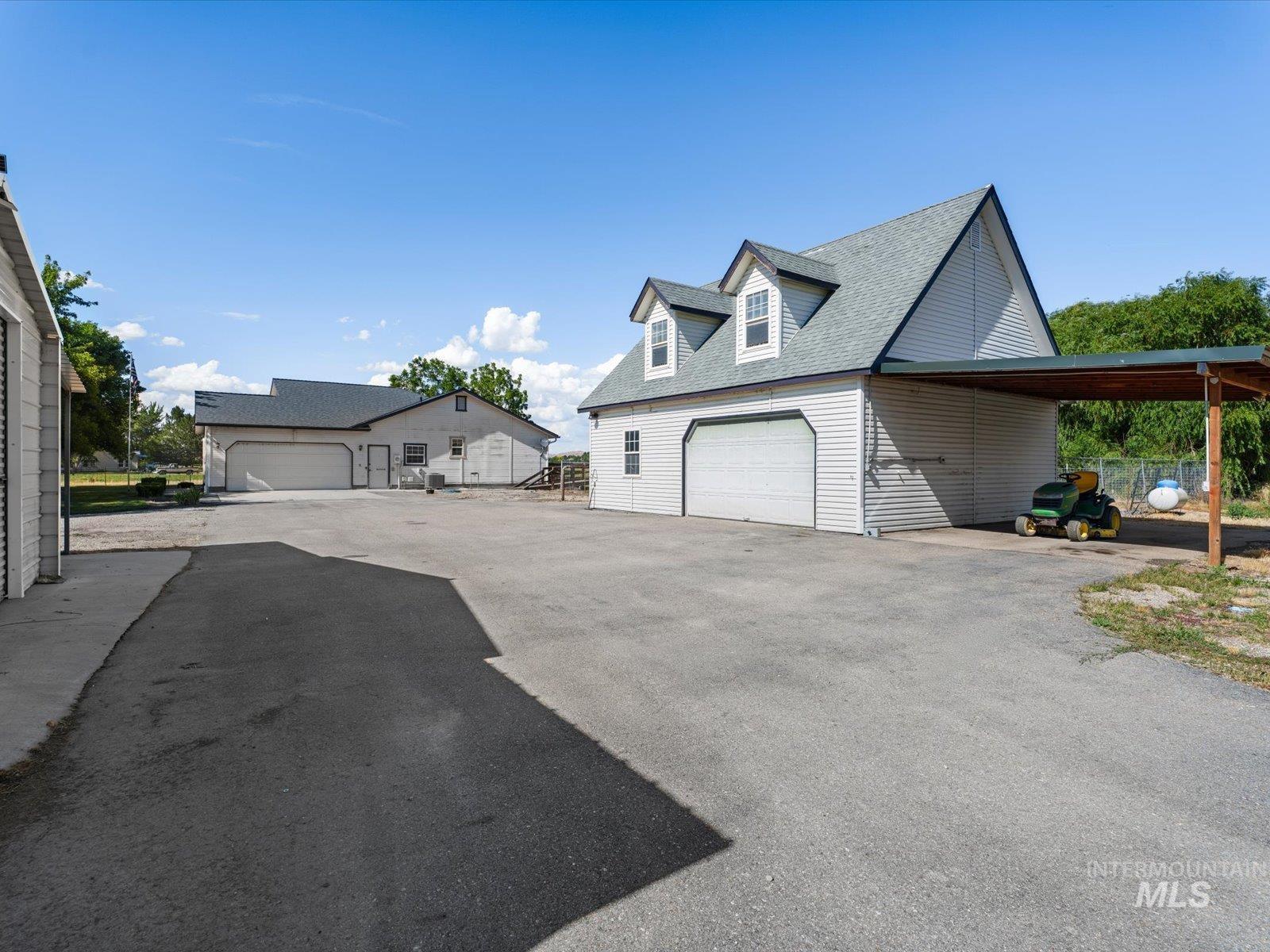 3540 Wills Road Emmett, ID 83617 - Photo 27 of 36 Multiple outbuildings with white siding and gray roofs, featuring an extended carport and a spacious paved drive