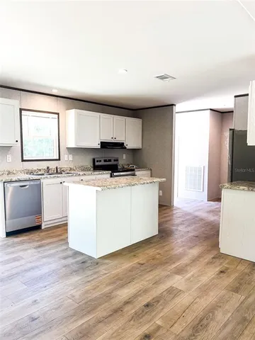 a kitchen with granite countertop a stove top oven sink and cabinets