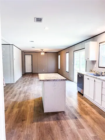 a living room with kitchen island granite countertop wooden floors and wide window