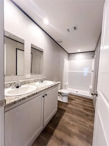 a bathroom with a granite countertop sink a toilet and shower