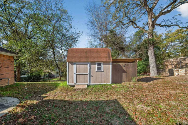 a backyard of a house with large trees and wooden fence