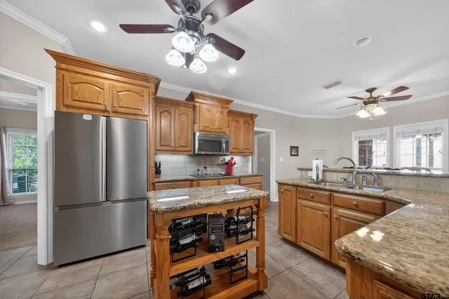 a kitchen with stainless steel appliances granite countertop a refrigerator a sink dishwasher a stove and white countertops with wooden floor