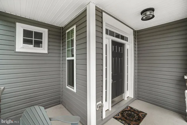 a view of a white house with a yard and table and chairs under an umbrella