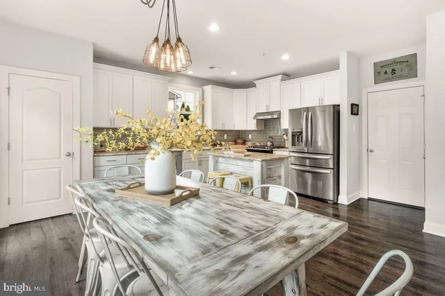 a kitchen with granite countertop a table chairs refrigerator and microwave