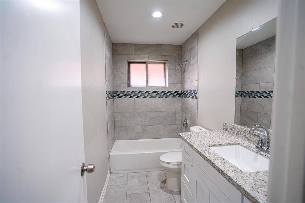 7130 Heath Street Houston, TX 77016 - Photo 12 of 18 a bathroom with a granite countertop sink a toilet and bathtub