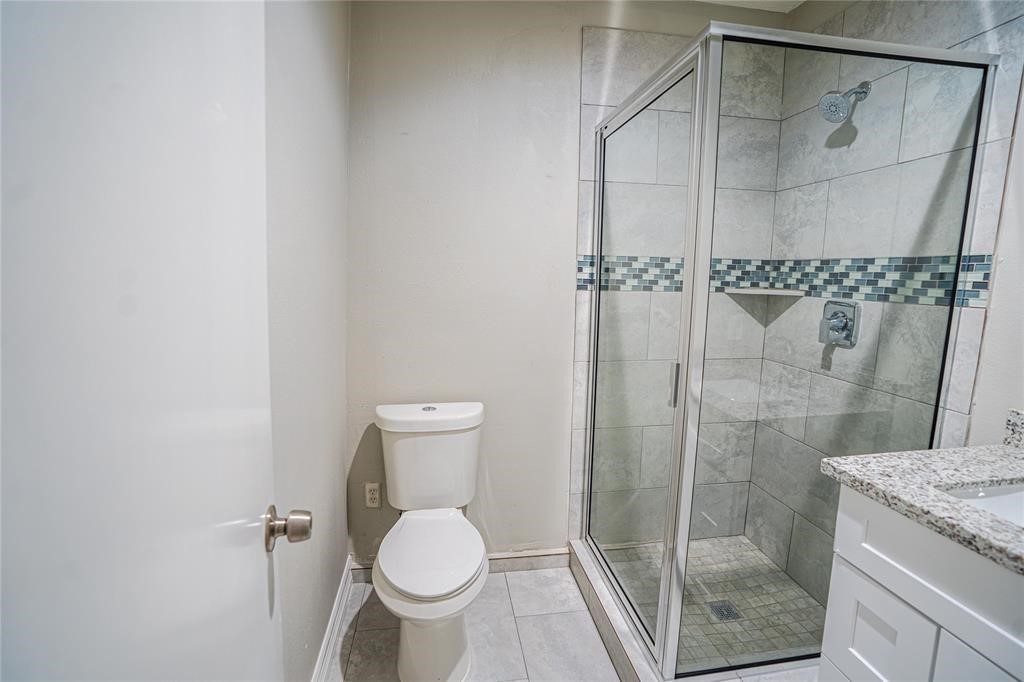 7130 Heath Street Houston, TX 77016 - Photo 13 of 18 a bathroom with a granite countertop shower and a toilet
