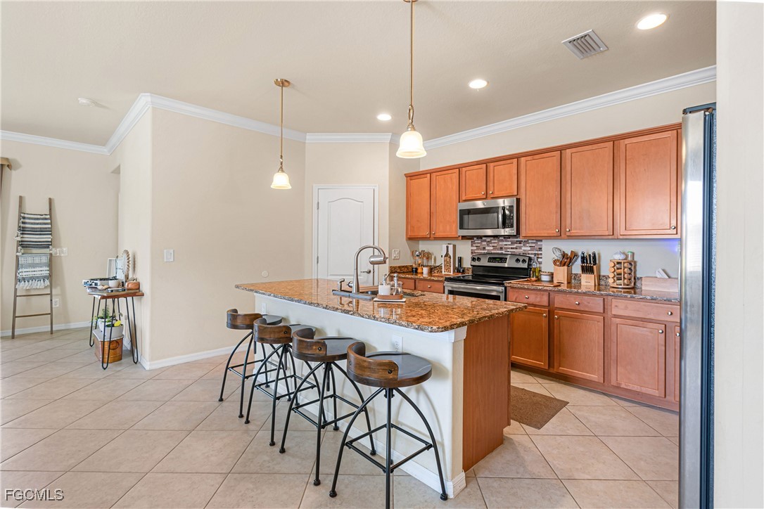 11656 Eros Road Lehigh Acres, FL 33971 - Photo 4 of 49 a kitchen with stainless steel appliances granite countertop a stove a sink a microwave a refrigerator and chairs