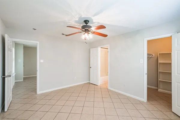 a view of an empty room and chandelier fan