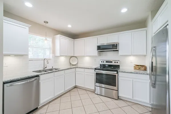 a kitchen with white cabinets stainless steel appliances and a window