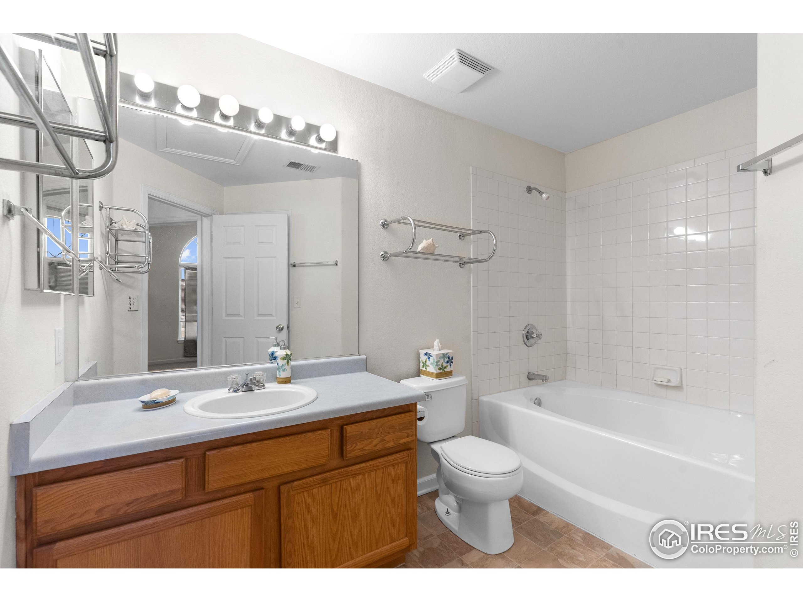 5151 29th Street, Unit 1311 Greeley, CO 80634 - Photo 13 of 16 a bathroom with a double vanity sink a toilet a mirror and shower