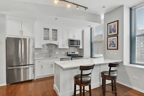 a open kitchen with stainless steel appliances granite countertop a sink dishwasher and a refrigerator with wooden floor