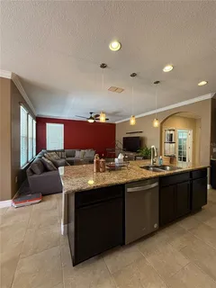a living room with furniture kitchen view and a large window