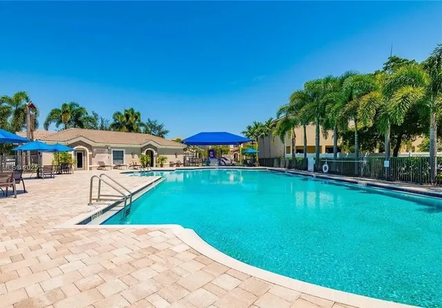 a view of swimming pool with lawn chairs and plants