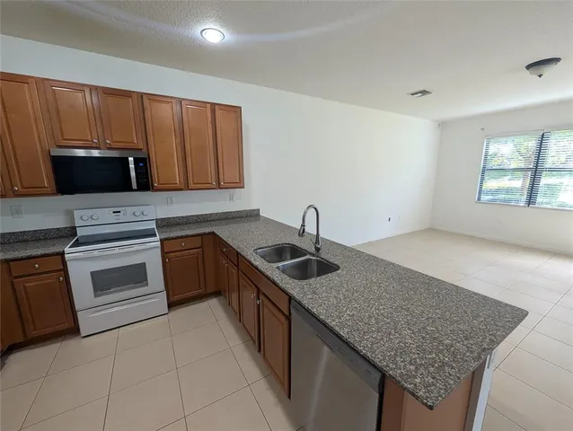 a kitchen with granite countertop a sink dishwasher stove and cabinets