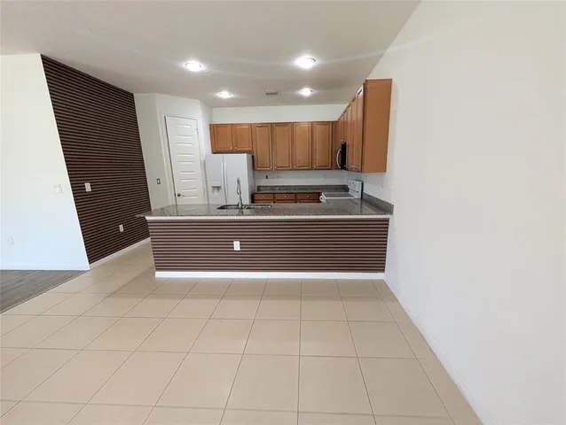 a view of kitchen with stainless steel appliances granite countertop a refrigerator and a sink