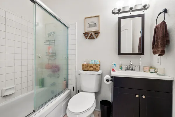 a bathroom with a toilet sink vanity tub and mirror