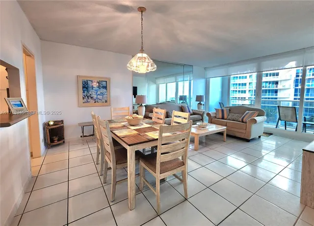 a view of a dining room and livingroom with furniture wooden floor a rug a flat screen tv and a large window